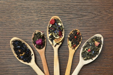 Photo of Flat composition with spoons of dried herbal tea leaves on wooden table