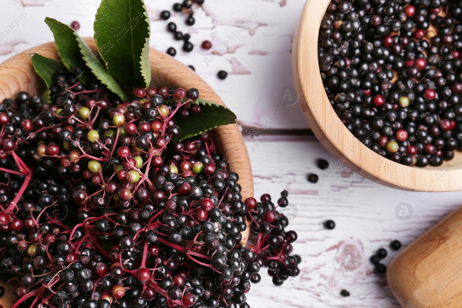 Photo of Tasty elderberries (Sambucus) on white wooden table, flat lay