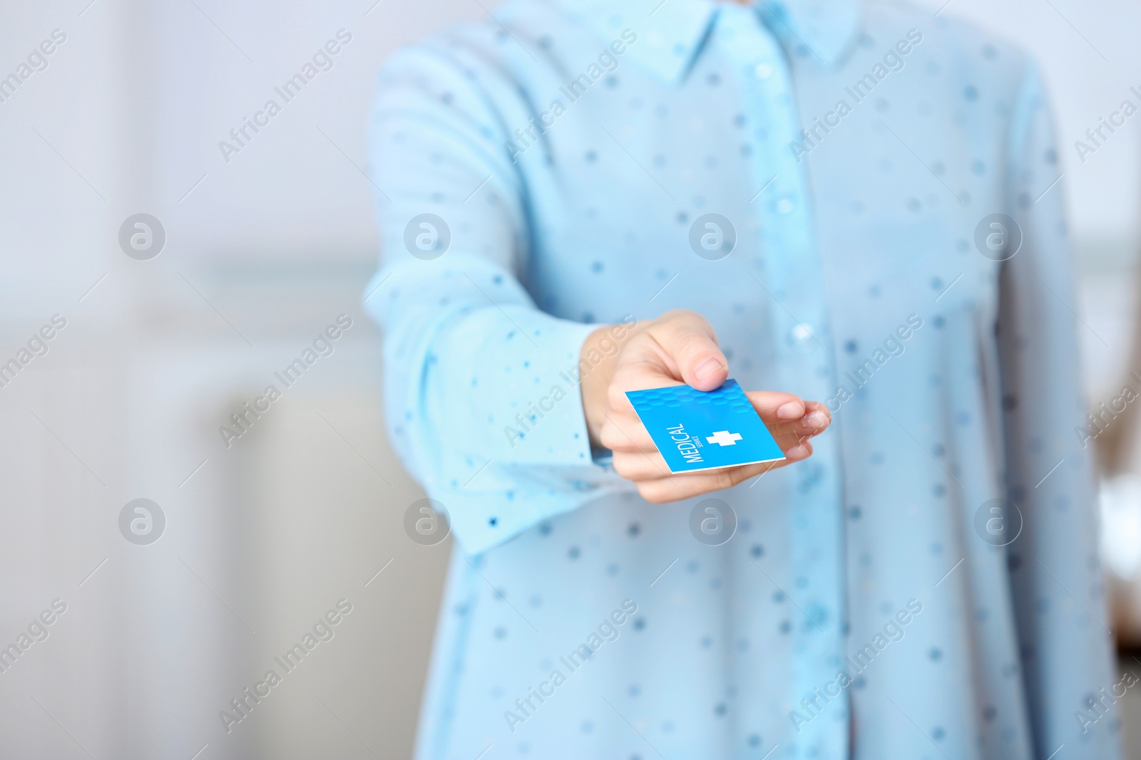 Photo of Woman holding business card indoors, closeup with space for text. Medical service