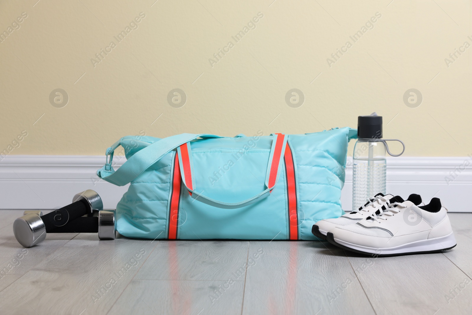 Photo of Bag with different sports equipment on wooden floor indoors