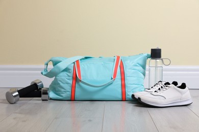 Photo of Bag with different sports equipment on wooden floor indoors