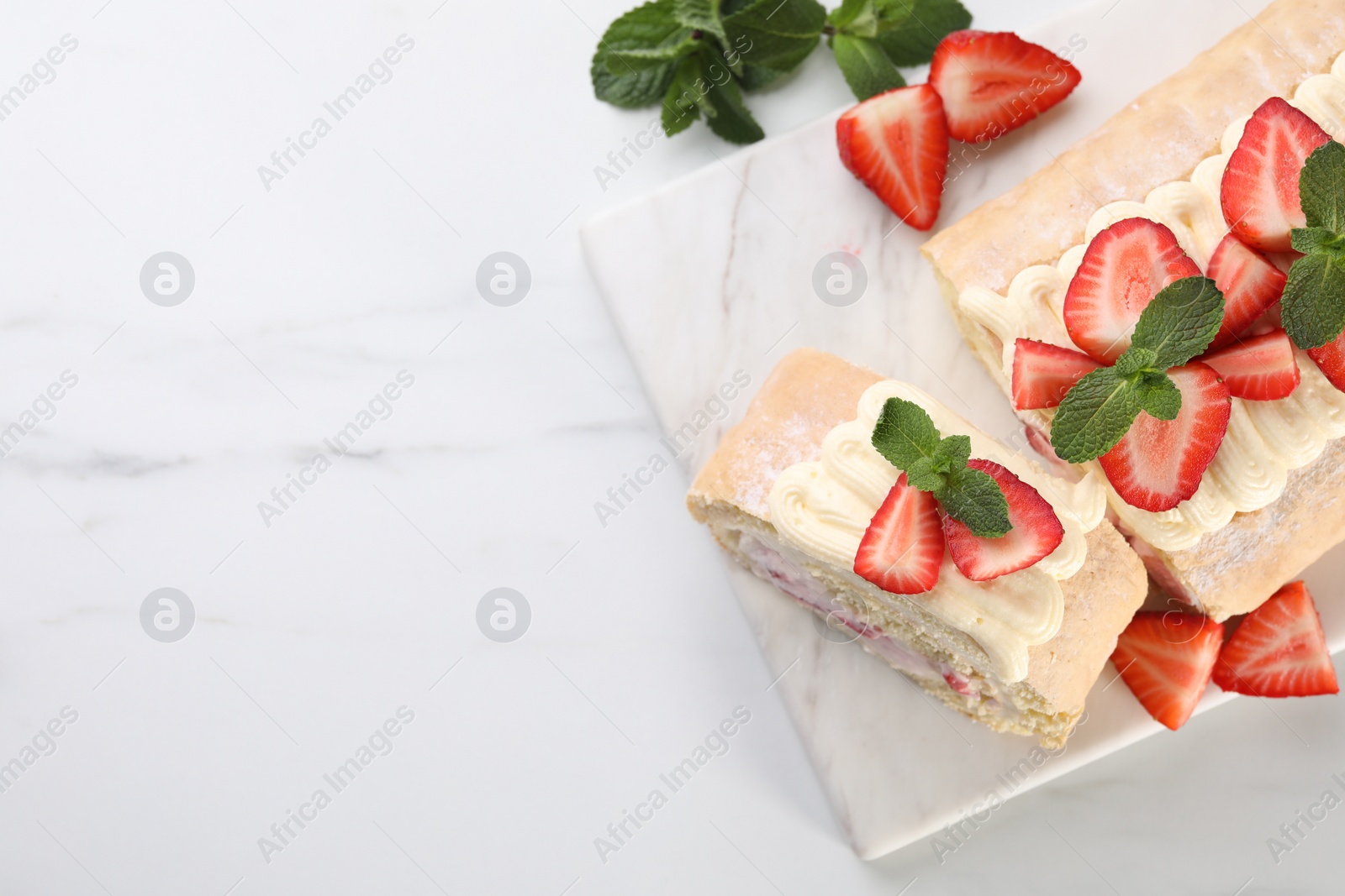 Photo of Delicious cake roll with strawberries and cream on white marble table, top view. Space for text