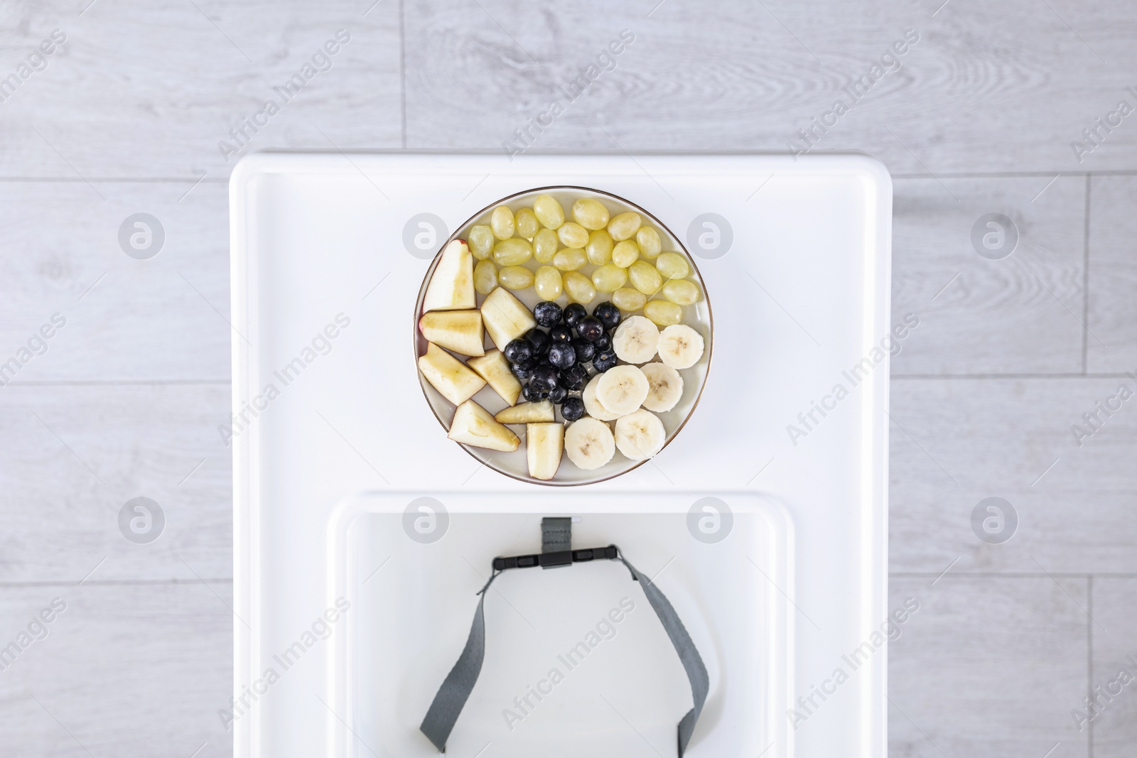 Photo of High chair with healthy baby food served on white tray indoors, top view