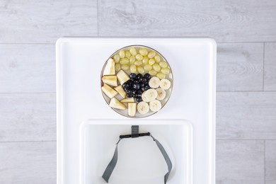 Photo of High chair with healthy baby food served on white tray indoors, top view