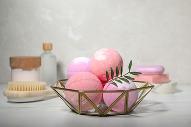 Beautiful aromatic bath bombs and green twig on white table, space for text