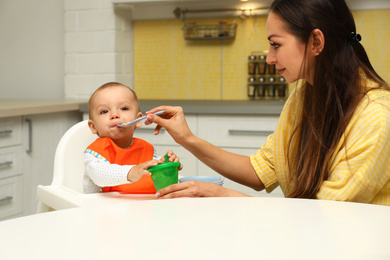 Young mother feeding her little baby at home