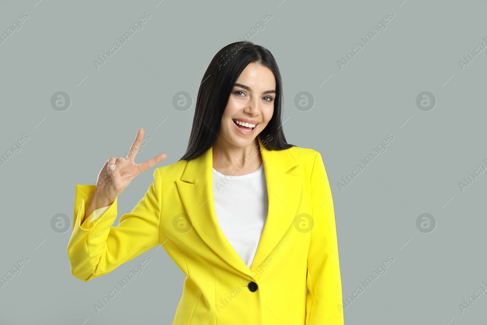 Photo of Woman showing number two with her hand on grey background