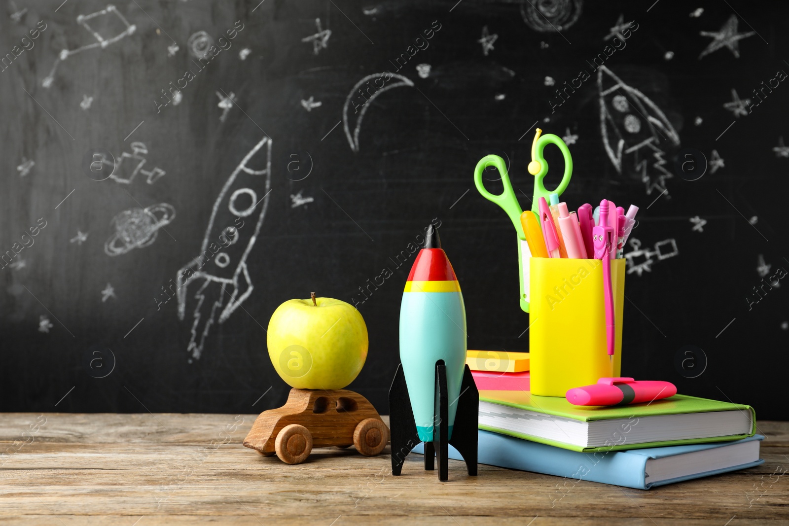Photo of Bright toy rocket, car and school supplies on wooden table