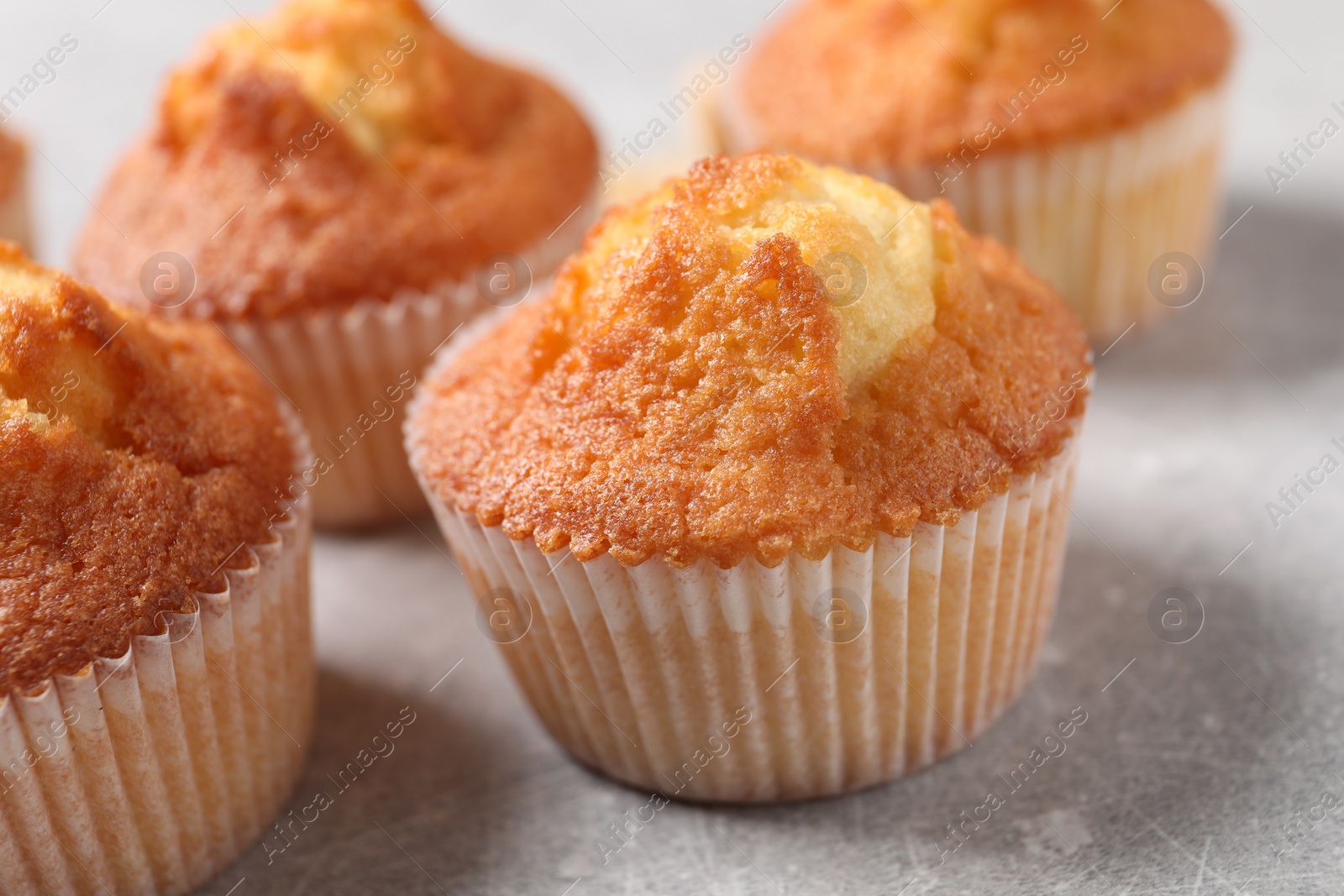 Photo of Delicious sweet muffins on light grey textured table, closeup