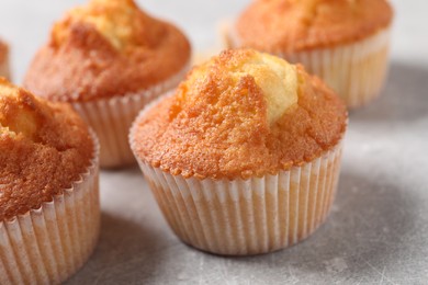 Delicious sweet muffins on light grey textured table, closeup