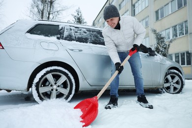 Photo of Man removing snow with shovel near car outdoors, low angle view