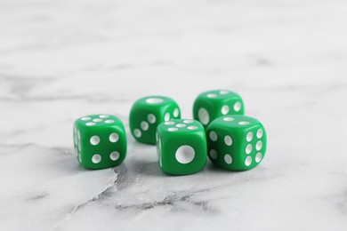 Photo of Many green game dices on white marble table, closeup