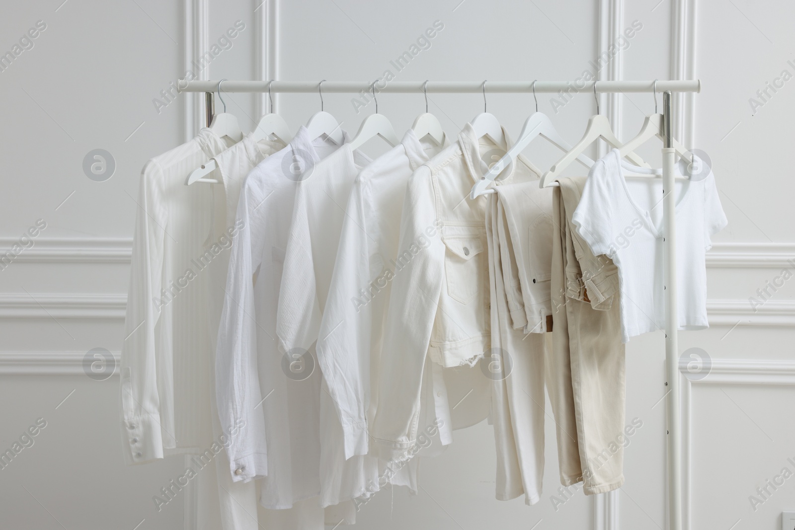 Photo of Rack with different stylish women`s clothes near white wall indoors