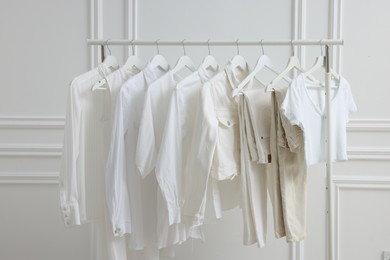 Rack with different stylish women`s clothes near white wall indoors