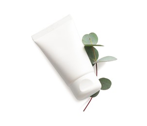 Photo of Tube of hand cream and eucalyptus on white background, top view