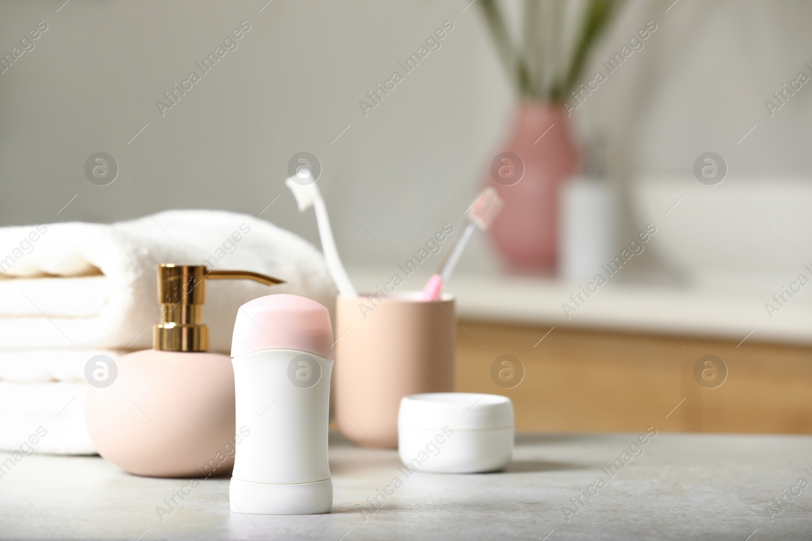 Photo of Stick deodorant and different toiletry on table in bathroom, space for text