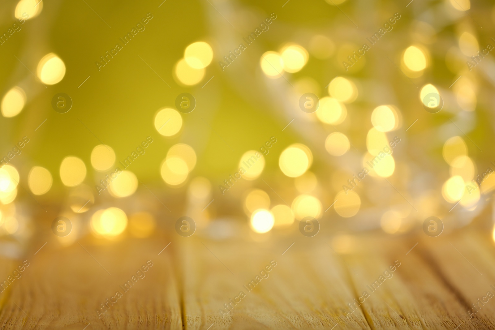 Photo of Yellow Christmas lights on wooden table, blurred view