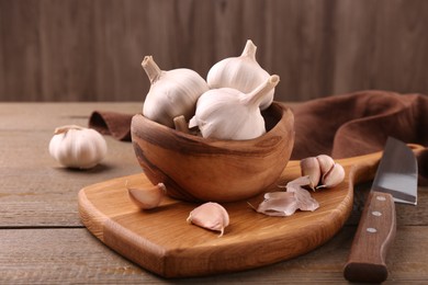 Fresh garlic and knife on wooden table, closeup