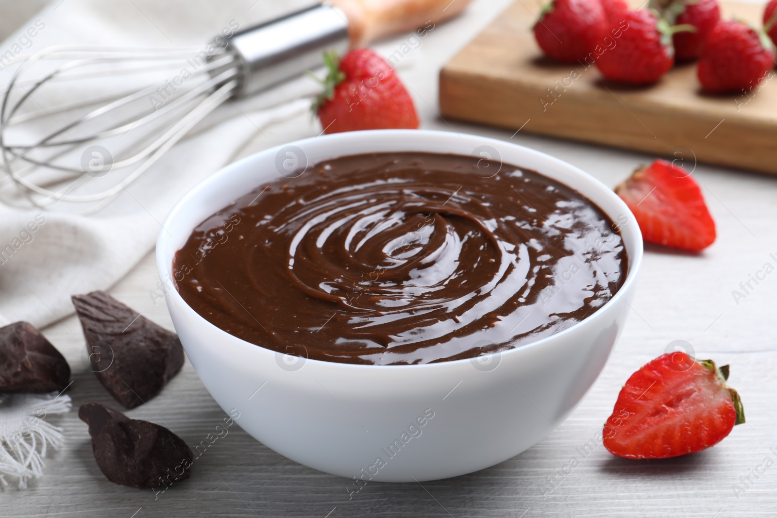 Photo of Delicious chocolate cream and strawberries on white wooden table, closeup