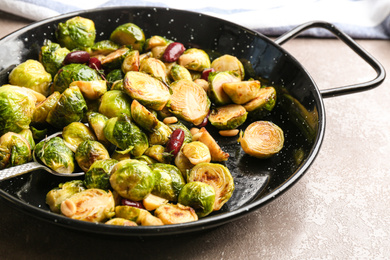 Photo of Delicious roasted brussels sprouts with red beans and peanuts on marble table, closeup