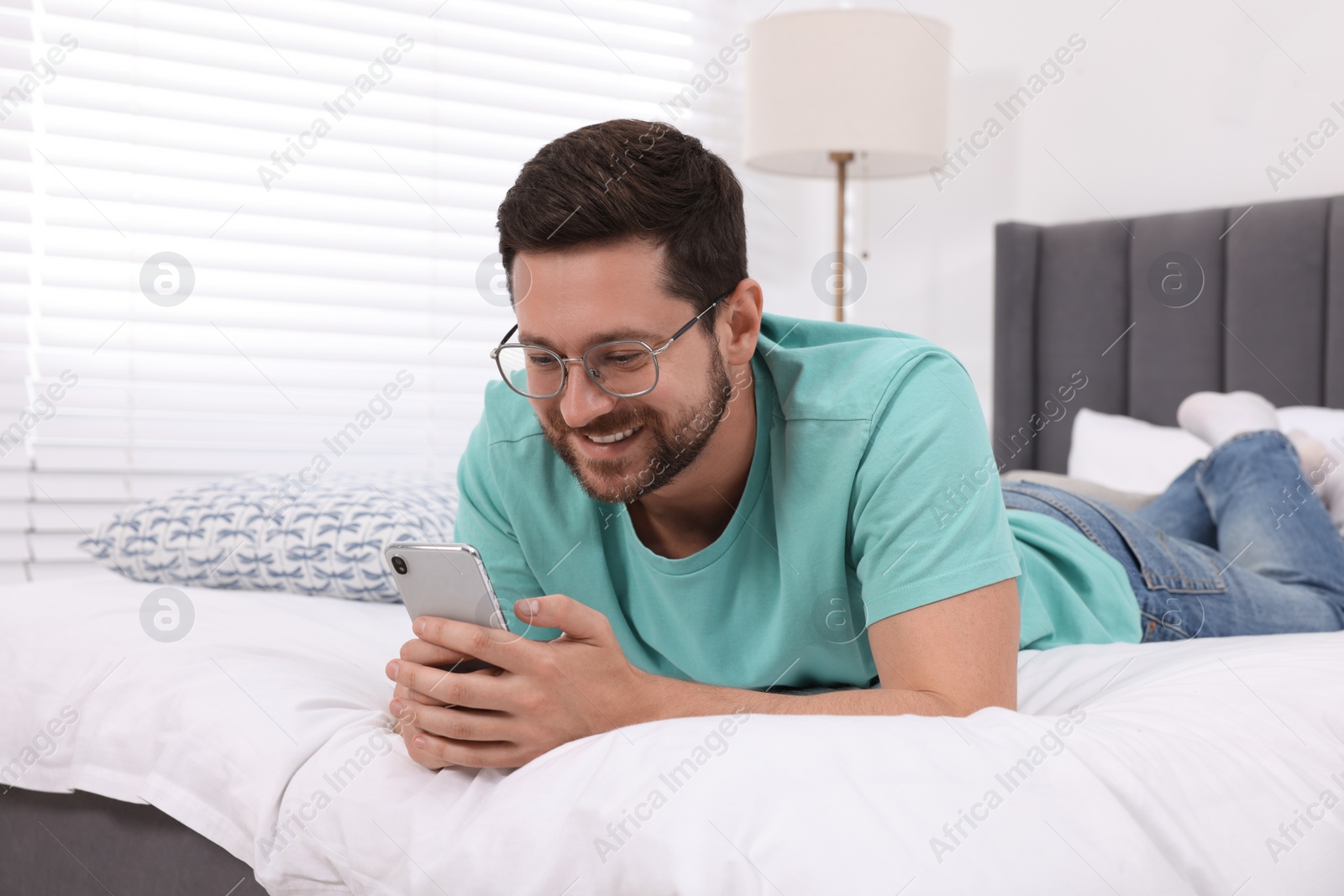 Photo of Happy man having video chat via smartphone in bedroom