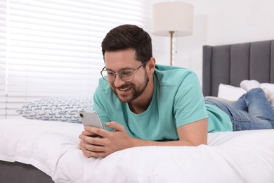 Happy man having video chat via smartphone in bedroom