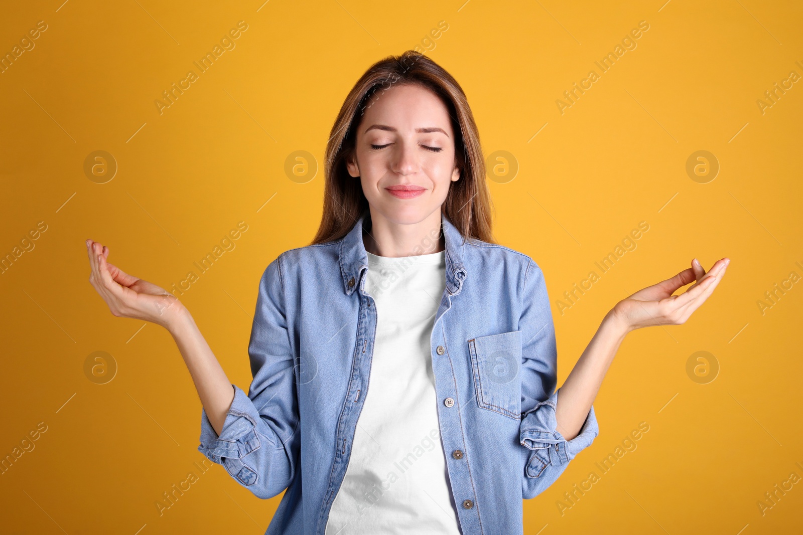 Photo of Young woman meditating on yellow background. Stress relief exercise