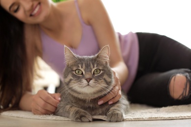 Photo of Young woman with cute cat at home, closeup. Pet and owner