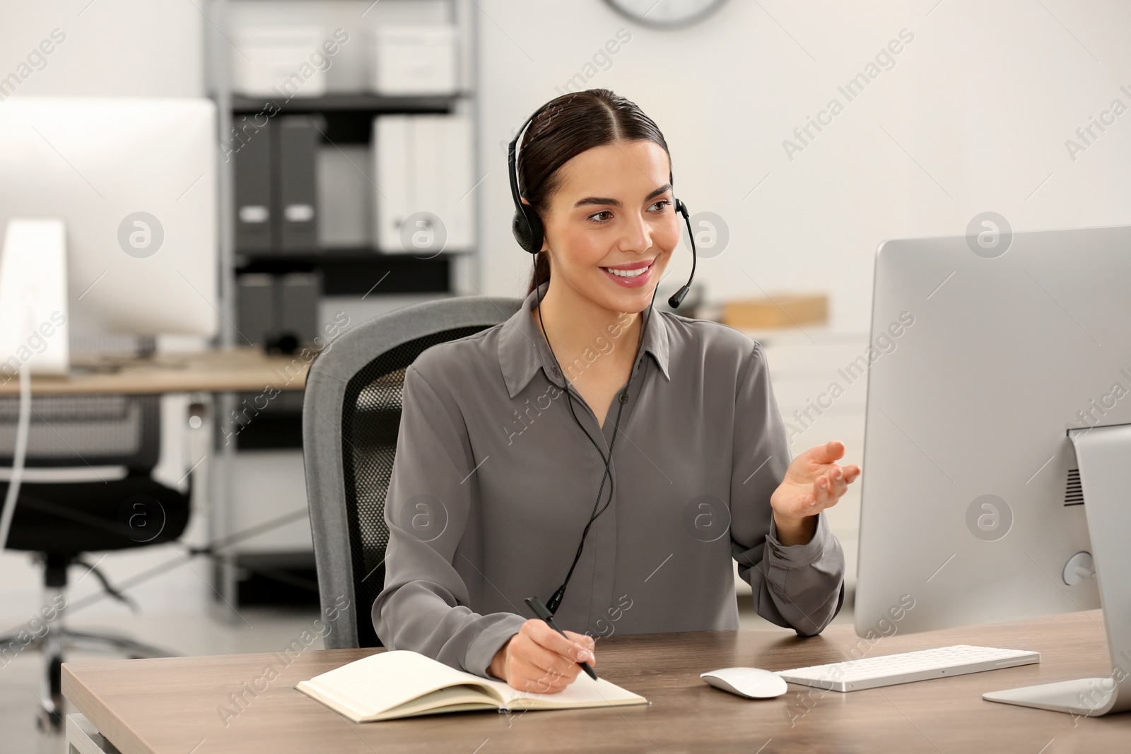Photo of Hotline operator with headset working on computer in office
