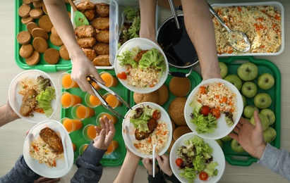 Photo of Volunteers serving food for poor people indoors, view from above