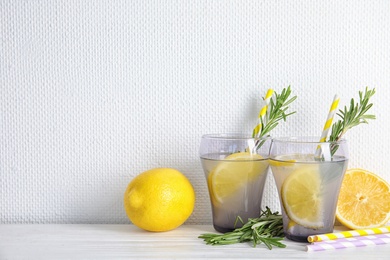 Glasses of fresh lemon cocktail with rosemary and space for text on light background