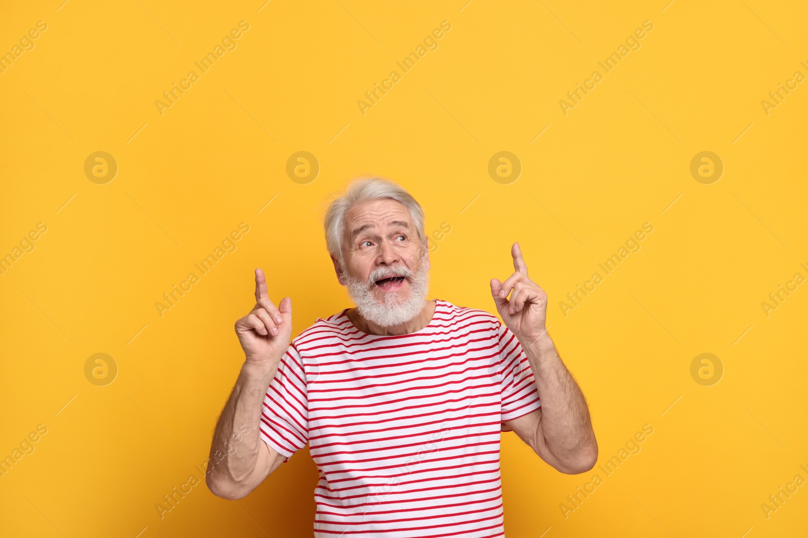 Photo of Senior man with mustache pointing at something on orange background