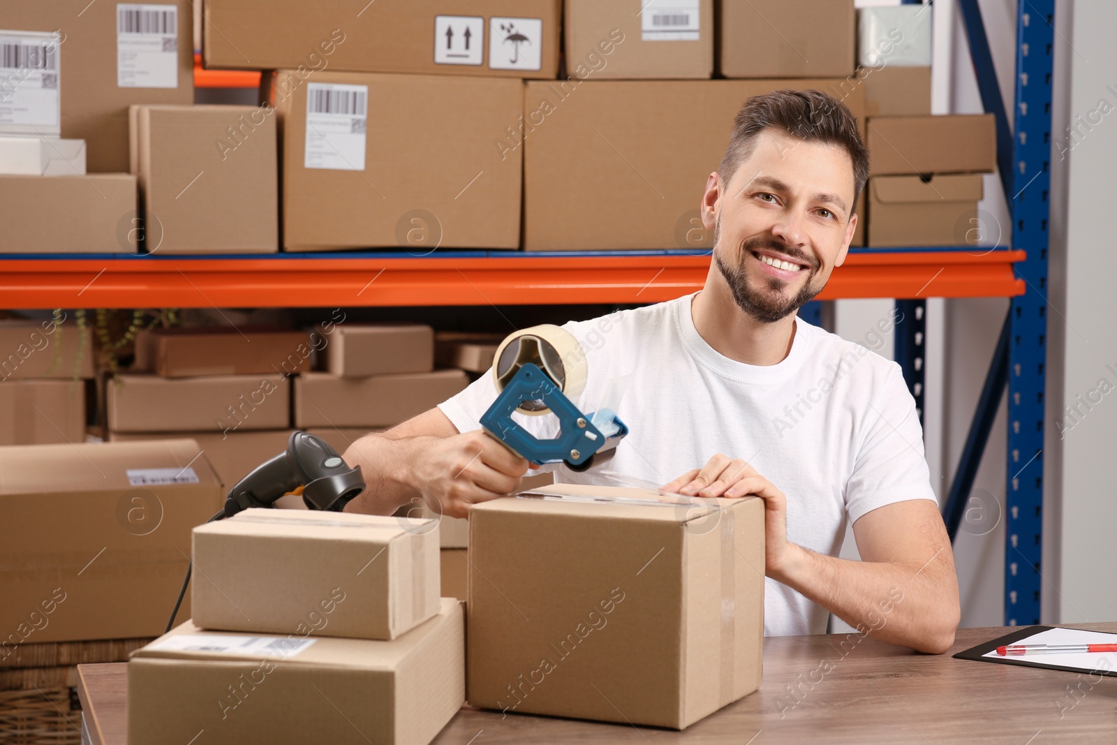 Photo of Post office worker packing parcel at counter indoors