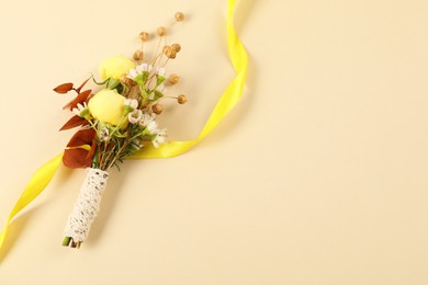 Photo of Stylish boutonniere and ribbon on beige background, top view. Space for text