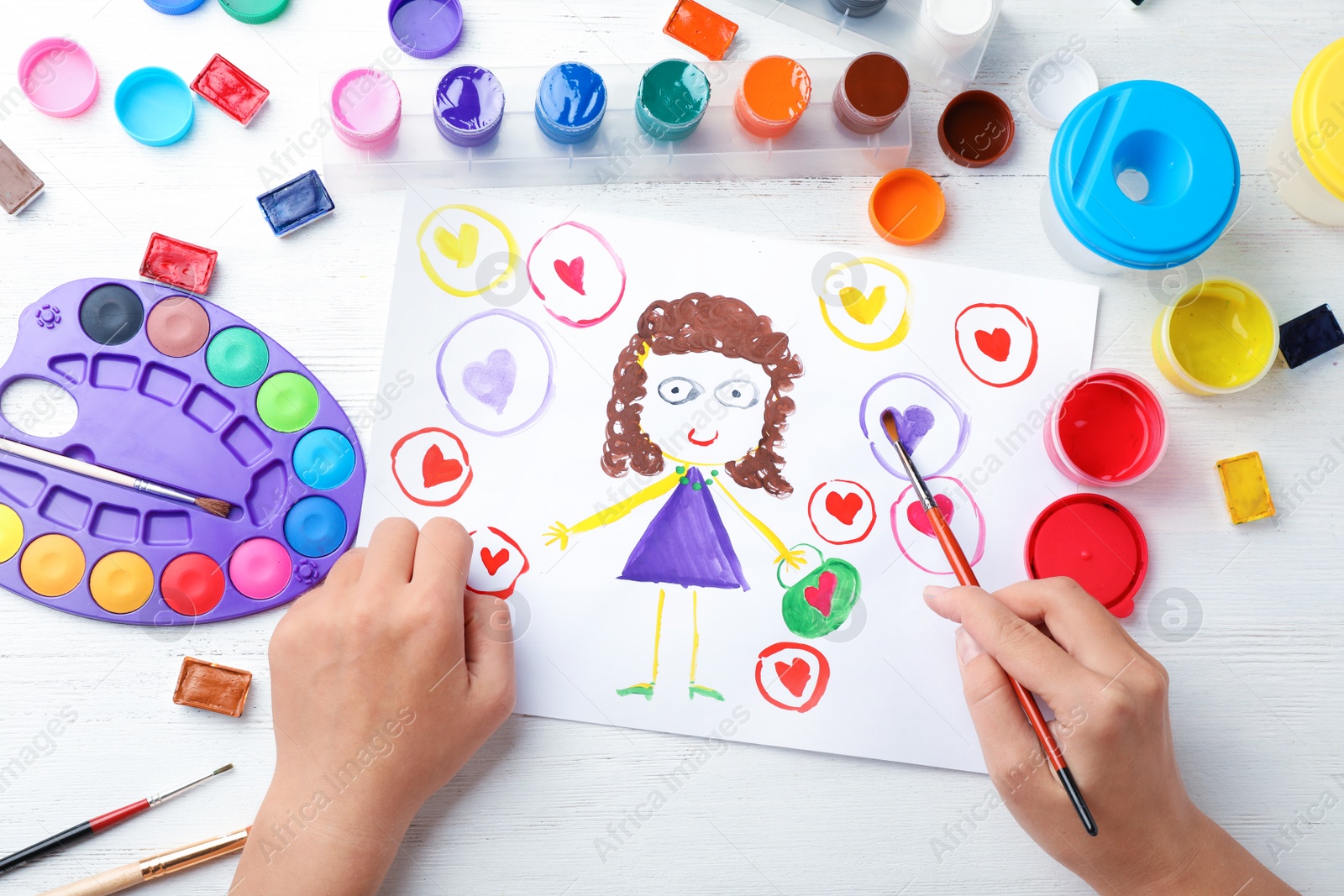 Photo of Girl painting picture of girl on table, top view