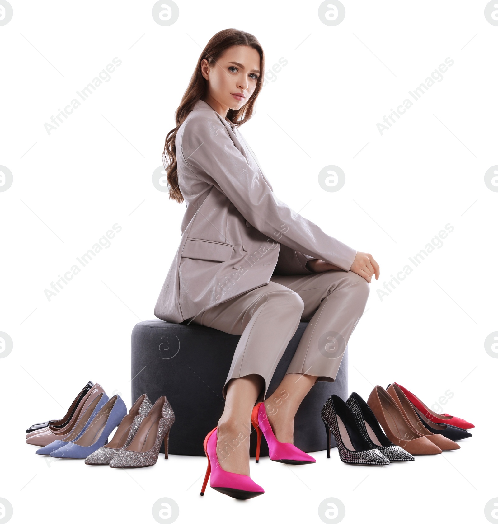 Photo of Fashionable young woman with many different high heel shoes on white background