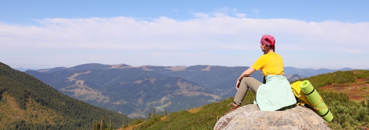 Young woman with backpack on peak in mountains, banner design