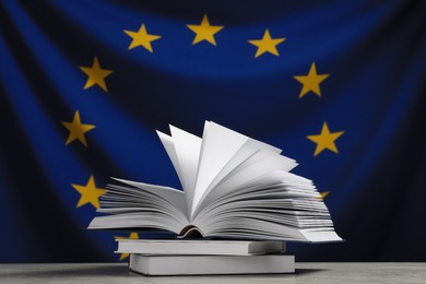 Photo of Books on light grey table against flag of European Union