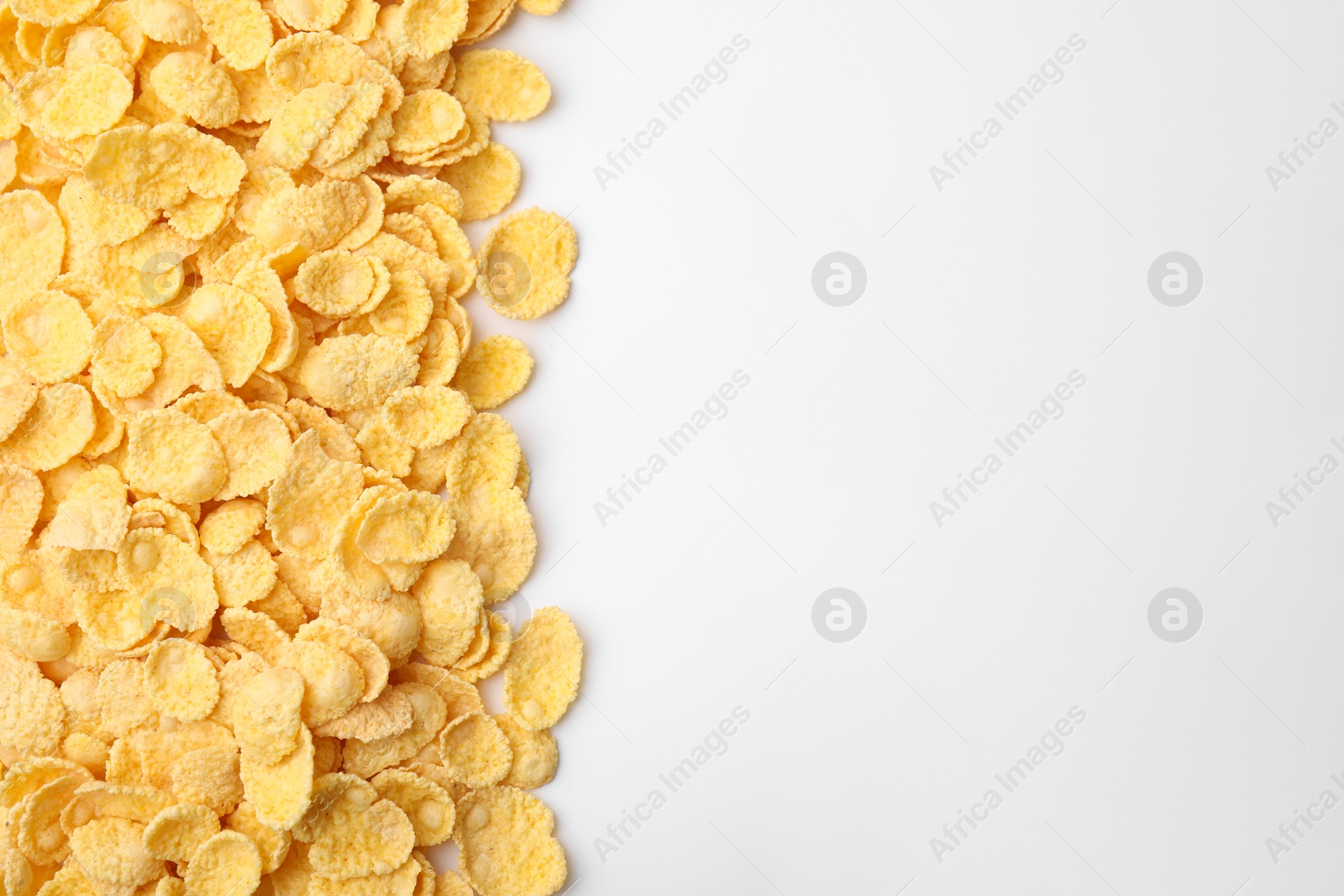 Photo of Breakfast cereal. Tasty corn flakes on white background, flat lay. Space for text