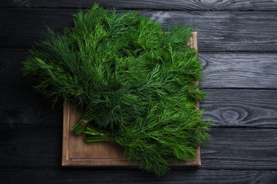 Photo of Bunches of fresh dill on black wooden table, top view