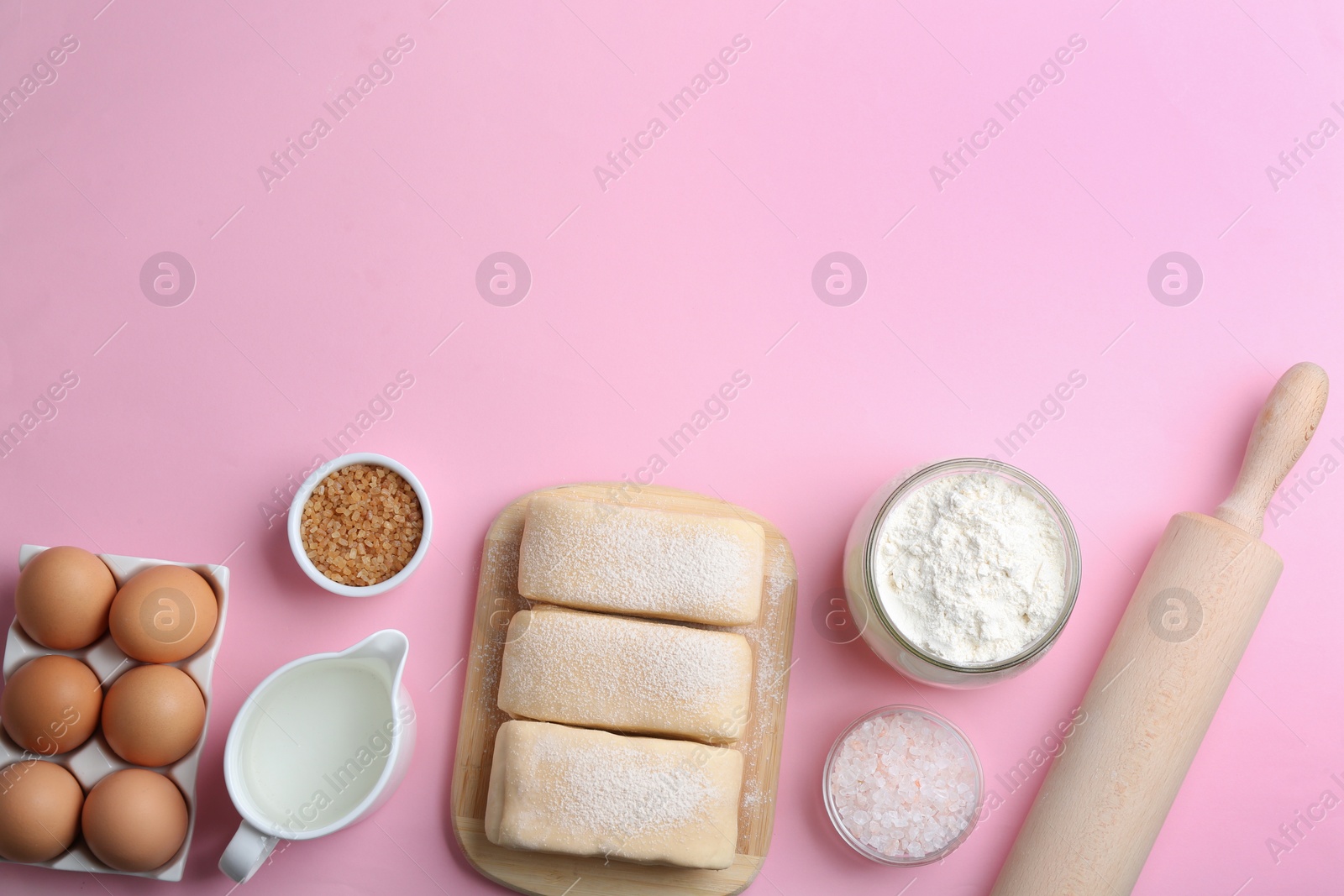 Photo of Puff pastry dough and ingredients on pink background, flat lay. Space for text