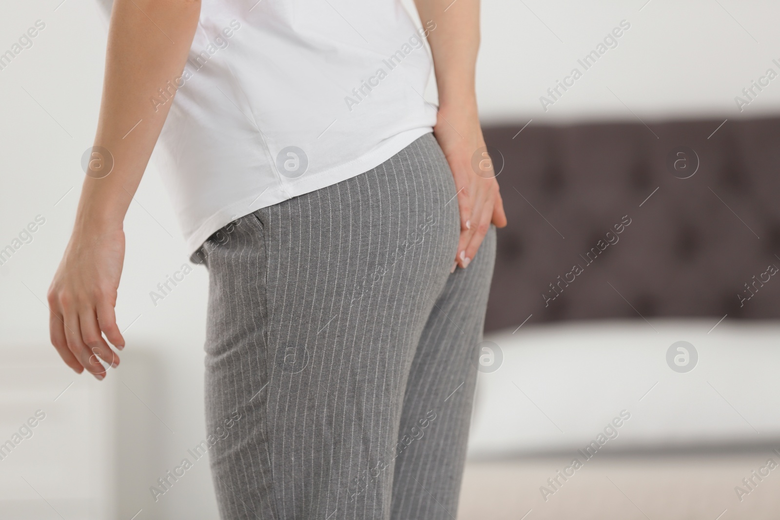 Photo of Young woman suffering from hemorrhoid at home, closeup