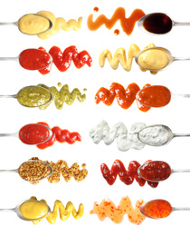 Set of spoons with different delicious sauces on white background, top view