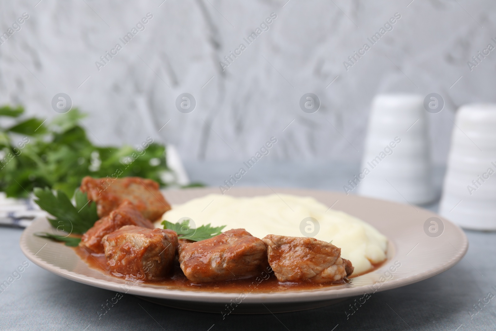 Photo of Delicious goulash served with mashed potato on light grey table, closeup. Space for text