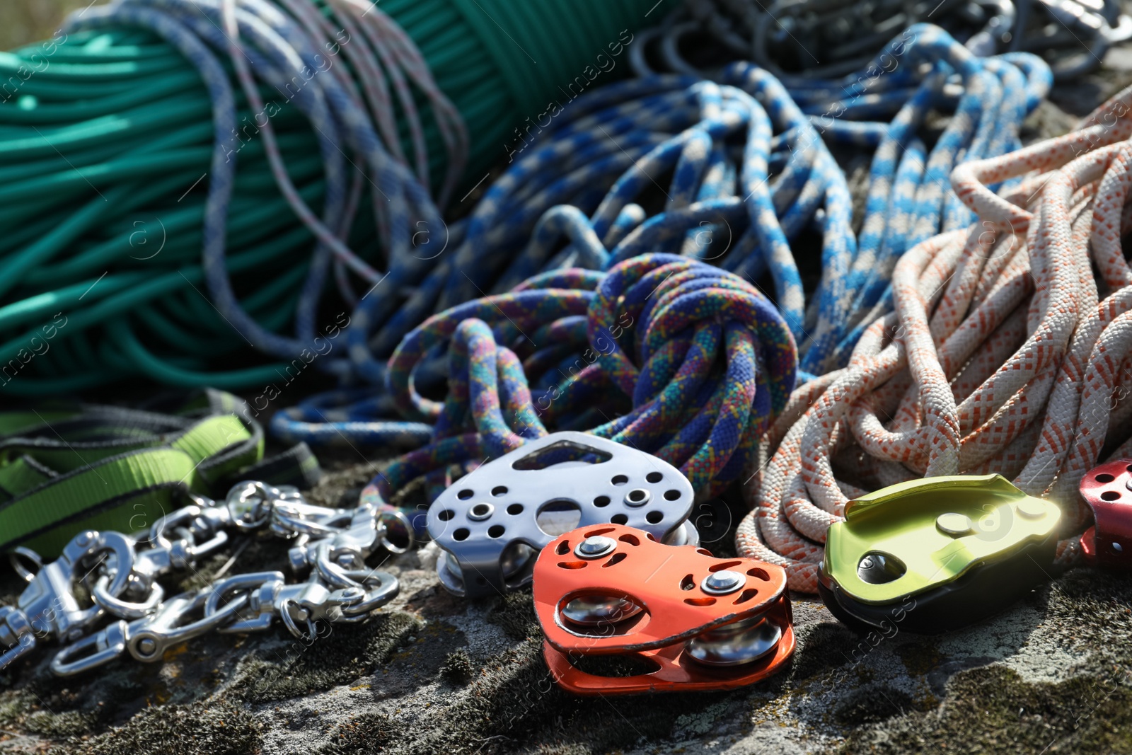 Photo of Different belay devices and ropes on rock, closeup. Climbing equipment