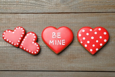 Photo of Decorated heart shaped cookies on wooden table, flat lay. Valentine's day treat