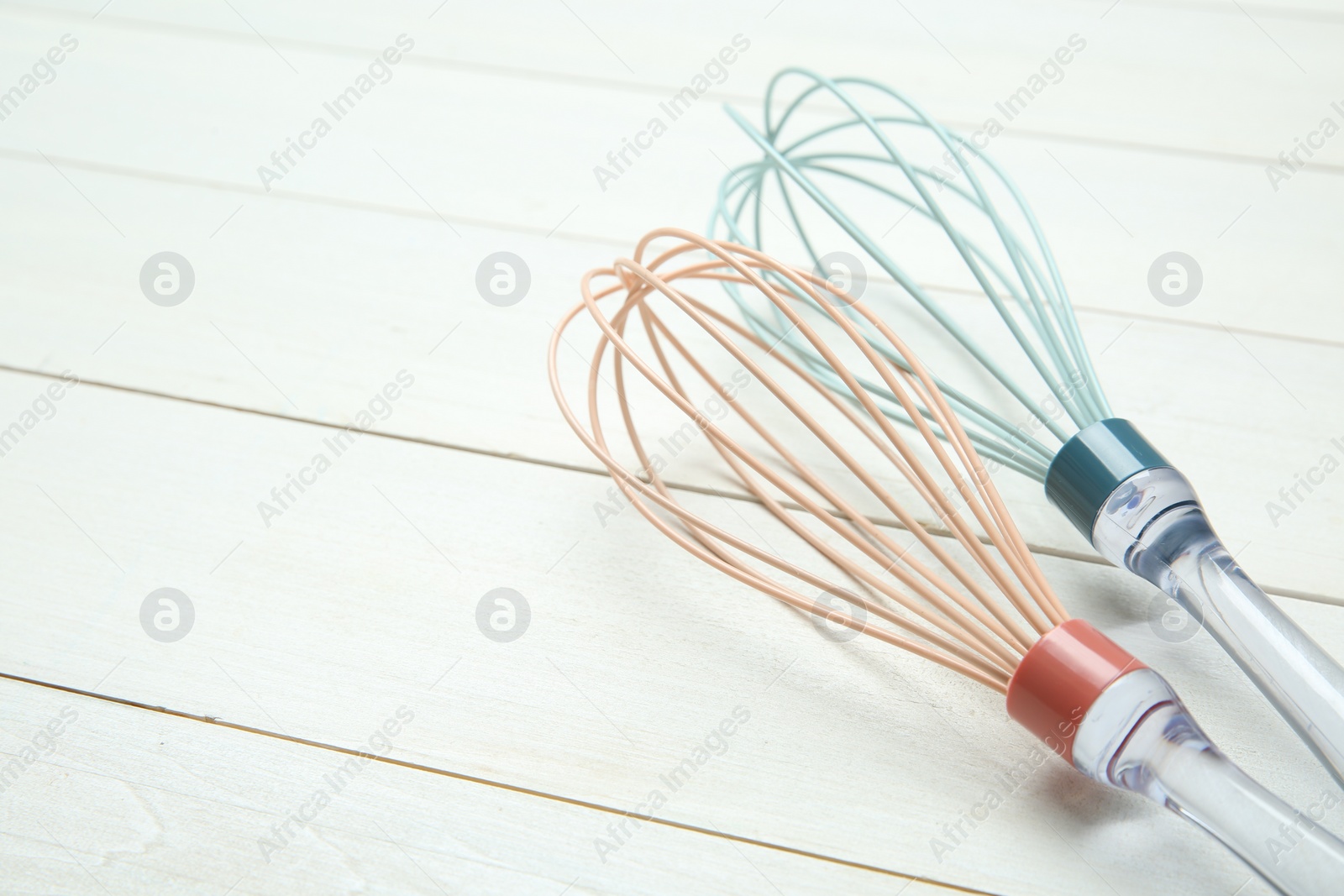 Photo of Two whisks on white wooden table, space for text