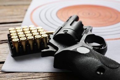 Photo of Shooting target, handgun and bullets on table, closeup