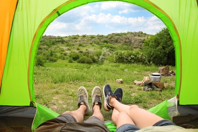 Photo of Young couple resting in camping tent, view from inside