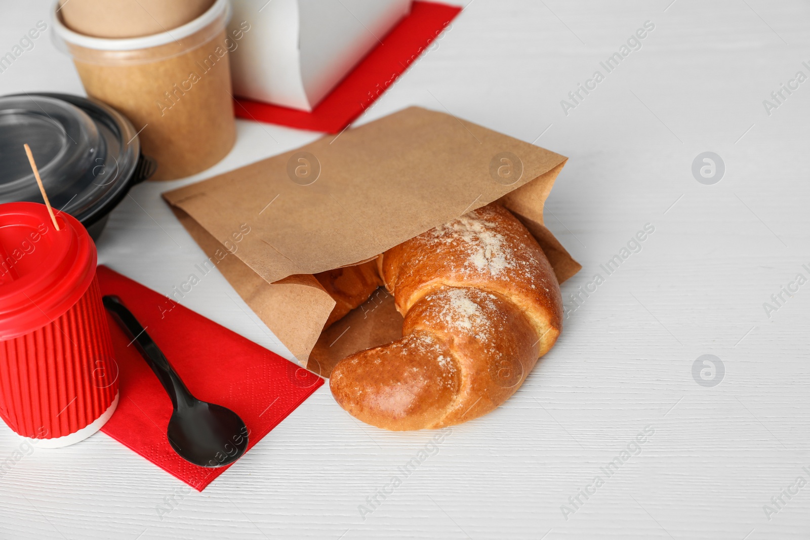 Photo of Paper bag with pastry and takeaway food on wooden table. Space for text